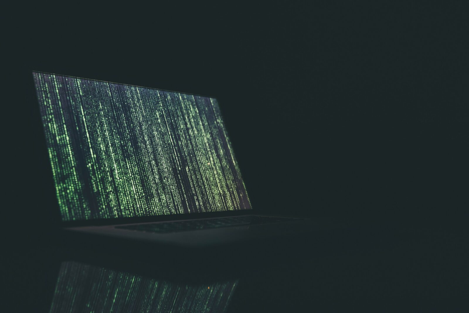 black and grey laptop computer turned on with green code