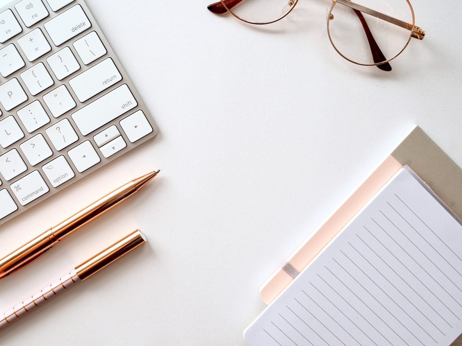 pen near black lined paper keyboard and eyeglasses