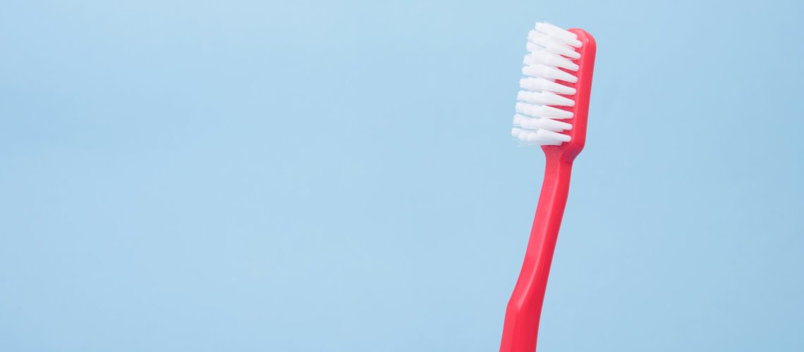 red toothbrush on the right side in front a of a blue background