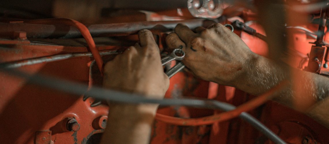 mechanic holding red metal frame of a car